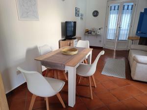 un soggiorno con tavolo in legno e sedie bianche di Appartamento Sole a Cala Gonone