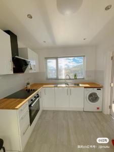 a kitchen with white cabinets and a sink and a window at Cloud Green apartment in Canley
