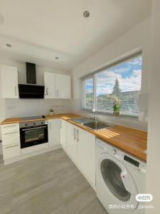 a kitchen with a sink and a washing machine at Cloud Green apartment in Canley