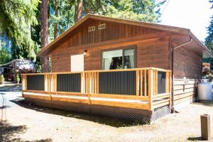 Cabaña de madera con porche grande en Riverbend Cottage & RV Resort, en Parksville
