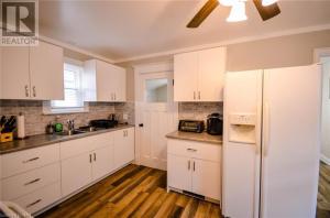 a kitchen with white cabinets and a white refrigerator at Cozy 3 Bedroom Downtown Hideaway Cottage with Complimentary Breakfast in Niagara Falls