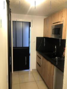 Habitación con cocina con microondas y puerta. en Résidence Héliovillage - Maisons & Villas pour 4 Personnes 804 - Naturiste, en Cap d'Agde