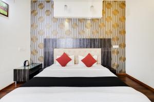 - une chambre avec un grand lit et des oreillers rouges dans l'établissement Capital O Hotel Shanti Nivas Near Hare Krishna Hill, à Bangalore
