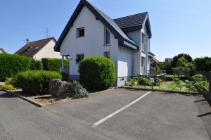 a white house with a parking lot at L'Hirondelle - Charming flat - in Blotzheim