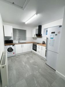 a kitchen with white cabinets and a white refrigerator at Cloud Green apartment in Canley