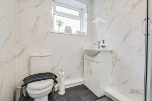 uma casa de banho branca com um WC e um lavatório em Stylish & Vibrant 2 BR Retreat Manchester em Manchester