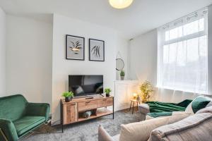 uma sala de estar com uma televisão de ecrã plano e mobiliário verde em Stylish & Vibrant 2 BR Retreat Manchester em Manchester