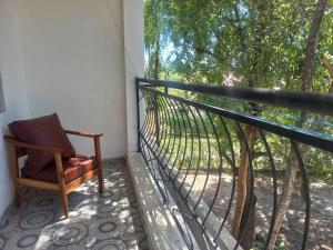 a chair sitting on a balcony next to a tree at Stay with Adhiambo in Kilifi