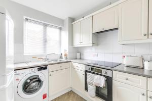 a kitchen with white cabinets and a washing machine at Welwyn Garden City Apartment by Mantis in Welwyn Garden City