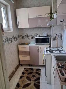 a small kitchen with a stove and a microwave at Apartament Cozy in Mediaş +4 photos