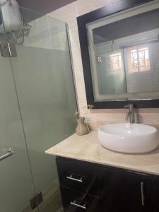 a bathroom with a sink and a glass shower at Ìtùnú at Molara's Villa in Abeokuta