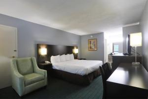 a hotel room with a bed and a chair at Greenville Inn & Suites in Greenville