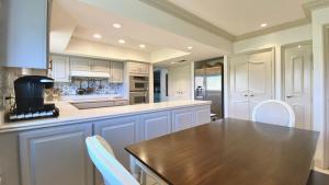 una cucina con armadi bianchi e tavolo in legno di LA DOLCE VITA VILLA 3 en-suites+large living spaces+glorious outdoor space:managed by Greenday a Rancho Mirage