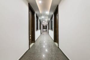 um corredor vazio de um edifício com paredes brancas e um longo corredor em Hotel Seven S em Nova Deli
