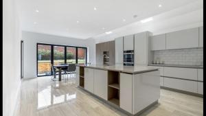 cocina con armarios blancos y comedor con mesa en Newly refurbished 3 bedroom property in north london, en East Barnet