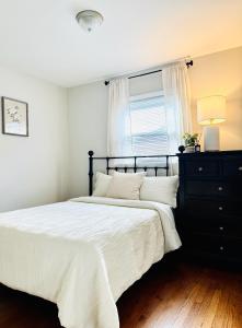 a bedroom with a bed with a black dresser and a window at Charming and Convenient 3br 1ba apt - fully furnished and equipped - fast Internet in Forest Park
