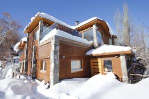 uma cabana de madeira na neve com neve em La Cornisa Lodge em Santiago