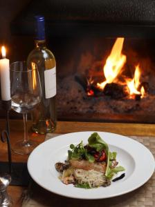 a plate of food and a glass of wine and a fireplace at La Cornisa Lodge in Santiago