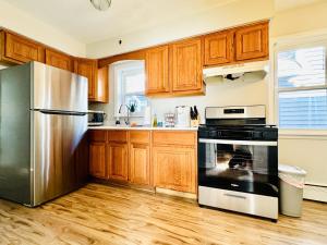 a kitchen with wooden cabinets and a stainless steel refrigerator at Charming and Convenient 3br 1ba apt - fully furnished and equipped - fast Internet in Forest Park