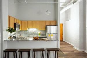 a kitchen with wooden cabinets and a counter with stools at TWO Bold 2BR 2BA Apartments by CozySuites in Indianapolis