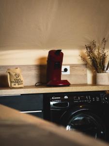 - une cafetière rouge installée au-dessus d'un lave-linge dans l'établissement L'aventurier, nuit insolite et hors du temps !, à Saumur