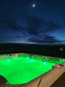 una piscina verde por la noche con la luna en el cielo en Loft Point 1 