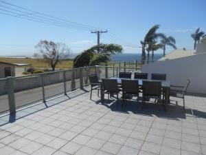 une terrasse avec une table et des chaises et l'océan dans l'établissement Adam's View Ardrossan, à Ardrossan