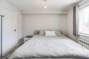 a white bedroom with a large bed in it at Welwyn Garden City Apartment by Mantis in Welwyn Garden City