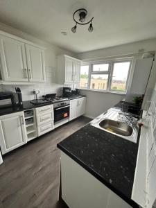 a kitchen with white cabinets and a black counter top at Gem In Enfield in Enfield
