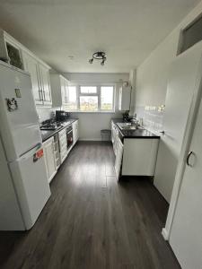 a kitchen with white appliances and a wooden floor at Gem In Enfield in Enfield