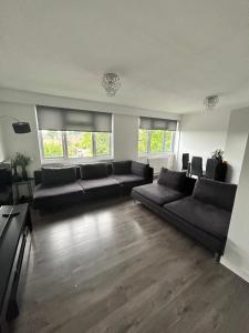 a living room with black couches and windows at Gem In Enfield in Enfield