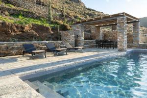 a pool with two chairs and a table next to a building at Triad Villas in Ioulis