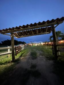 eine hölzerne Pergola auf einer unbefestigten Straße neben einem Zaun in der Unterkunft Chalé Canastra Zoo in Capitólio