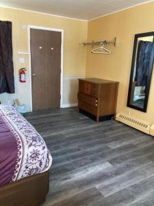 Pine Ridge Motel في تيمينز: غرفة نوم بسرير وخزانة ومرآة