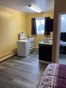 eine Küche mit einem Herd und einem Waschbecken in einem Zimmer in der Unterkunft Pine Ridge Motel in Timmins