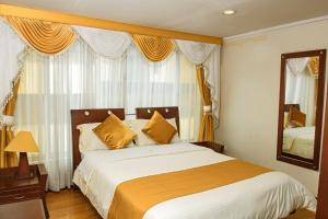 ein Schlafzimmer mit einem großen Bett und einem Spiegel in der Unterkunft Hotel Senegal in Pasto