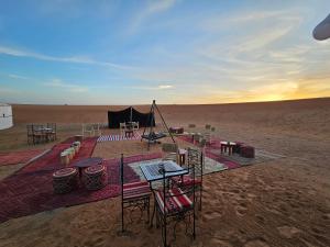 Najma Luxury Camp في مرزوقة: خيمة في الصحراء مع طاولات وكراسي