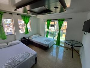 a bedroom with two beds and a table and windows at HOTEL DULCES SUEÑOS in Buenaventura