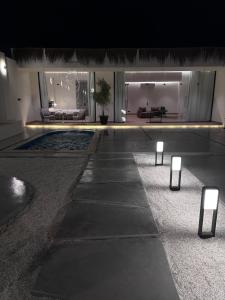 a building with a pool with lights on the ground at شاليه الجبل ( 2 ) in Ḑubā
