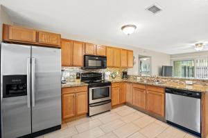 een keuken met houten kasten en roestvrijstalen apparatuur bij Cozy 2-Bedroom Condo in Prime Siesta Key Location in Sarasota