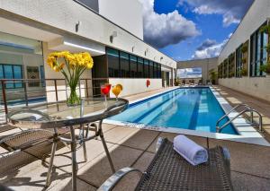 a glass table with a vase of flowers next to a swimming pool at Flat 609 - Comfort Hotel Taguatinga in Brasilia