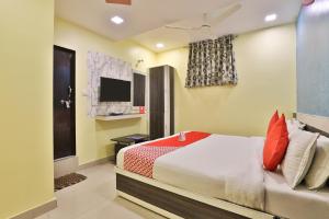 a bedroom with a bed with red pillows and a tv at Hotel Green Land in Ahmedabad
