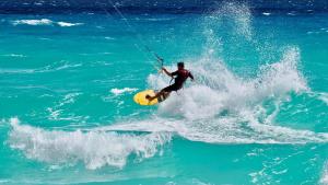 un hombre montando una ola en una tabla de surf en el océano en Solymar Beach Condos en Cancún