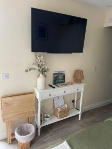 a white table with a television on a wall at The Cotswold Nook in Dursley