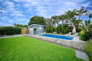 a backyard with a swimming pool and green grass at Golden Beach Family Relaxation in Golden Beach