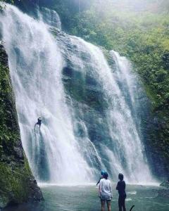 two people standing at the bottom of a waterfall at Reserva La Esperanza in Vergara