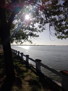 a tree and a fence next to a body of water at El Destino in San Miguel del Monte