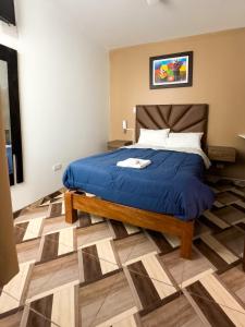 a bedroom with a bed with a blue comforter at HOTEL NILA in Cajamarca