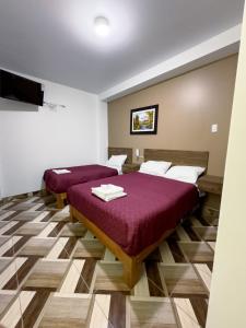 a room with two beds and a flat screen tv at HOTEL NILA in Cajamarca