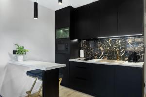 a kitchen with black cabinets and a white counter at Apartament Park Partynice in Wrocław